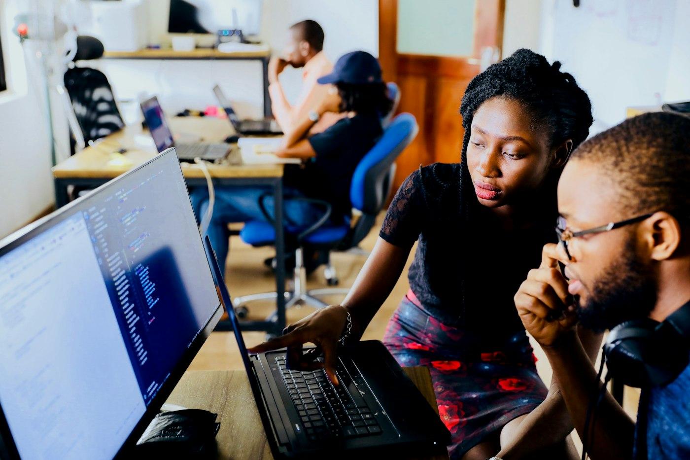 A developer and her mentee working through code together on a laptop.